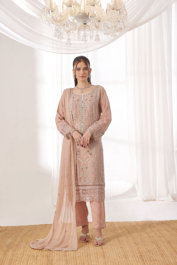Woman wearing a light pink traditional outfit with a sheer dupatta in a well-lit room.