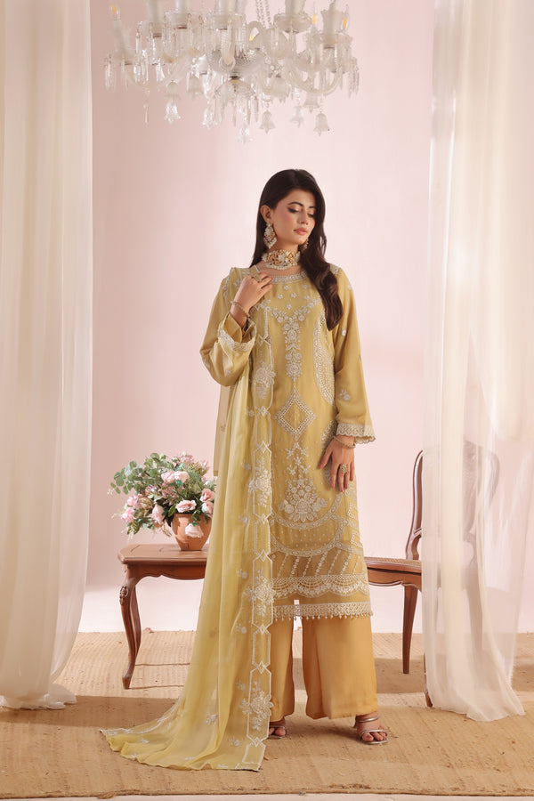Woman in a yellow embroidered outfit standing in a decorated room with curtains and a chandelier.